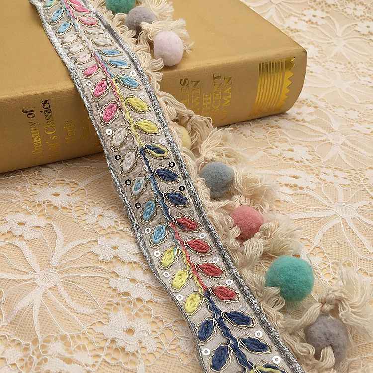 Long ribbon trim with colorful embroidery and fluffy fringe pom-poms