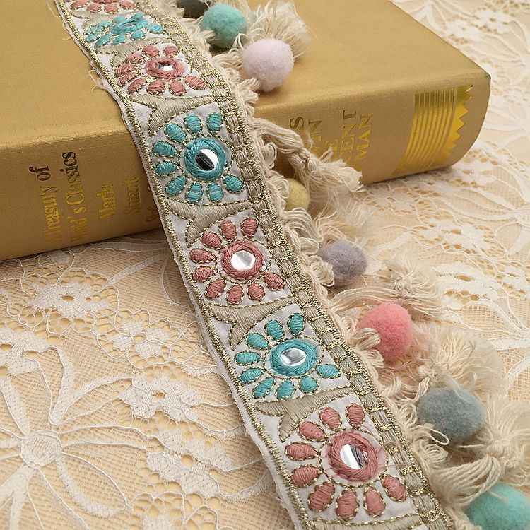 Embroidered jacquard lace trim with floral medallions and teal/pink pom-poms