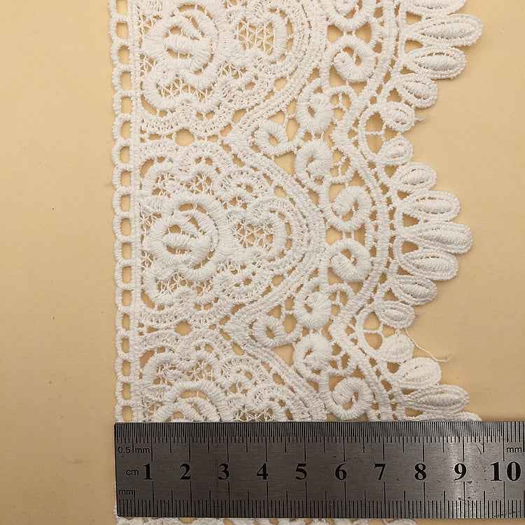 White cotton lace trim with floral embroidery detail; width shown with measuring tape