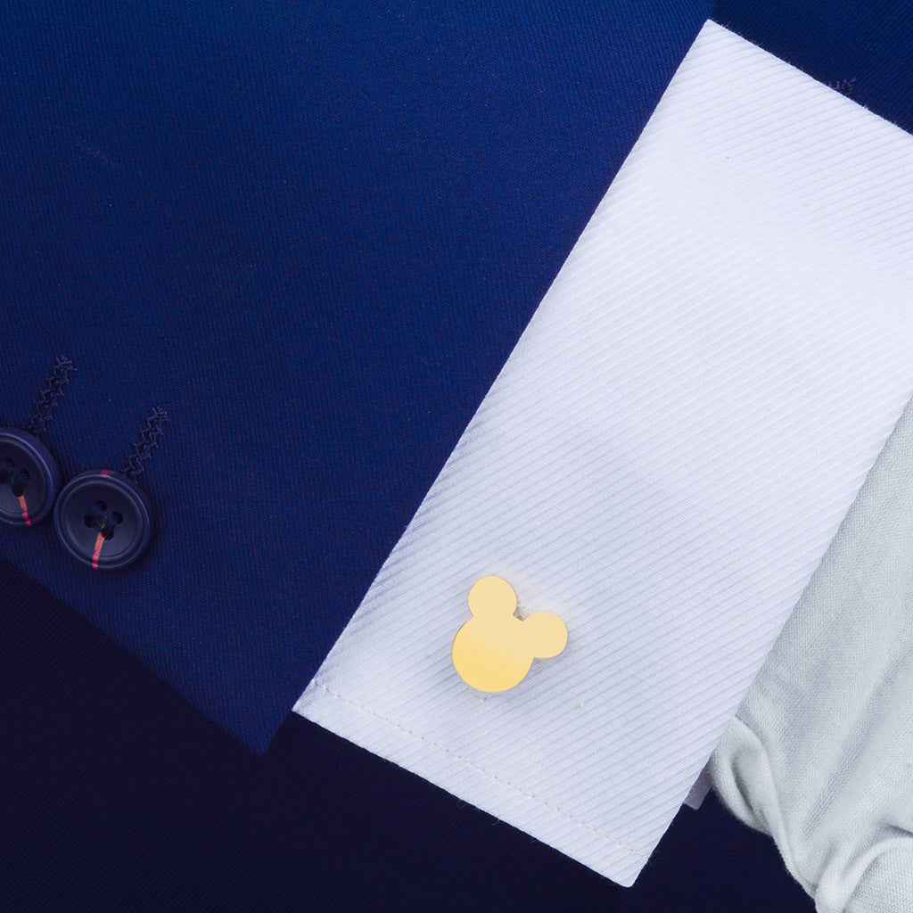 Gold Mickey Mouse cufflink on shirt cuff, glossy metal Mickey emblem