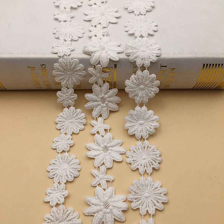 White lace trim with assorted flower rosettes and layered petal textures