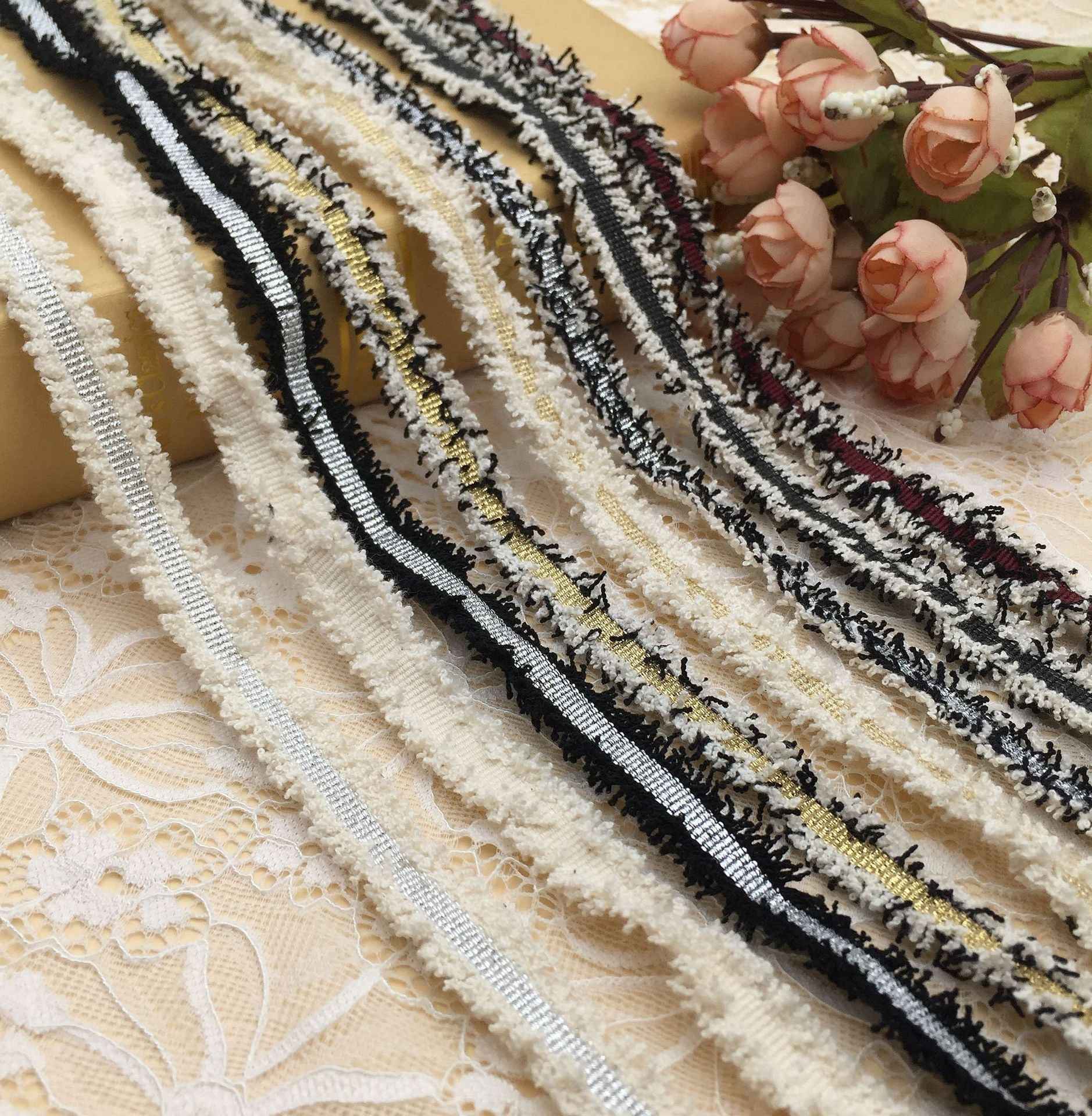 Metallic fringe trim with gold and silver stripes on white, plus black stripe detail