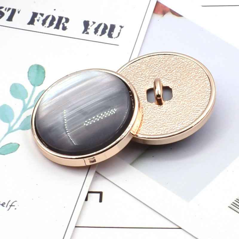 Cat-eye resin coat button: dark gray oval front with gold metal shank and textured back.