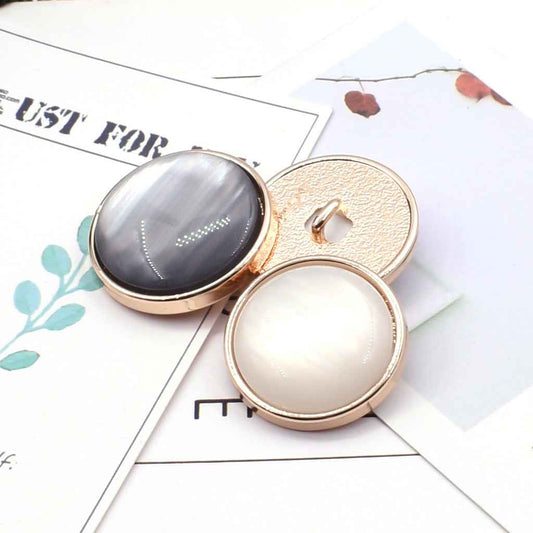 Cat-eye coat button pair: gray front with metal shank and textured back, plus white button.