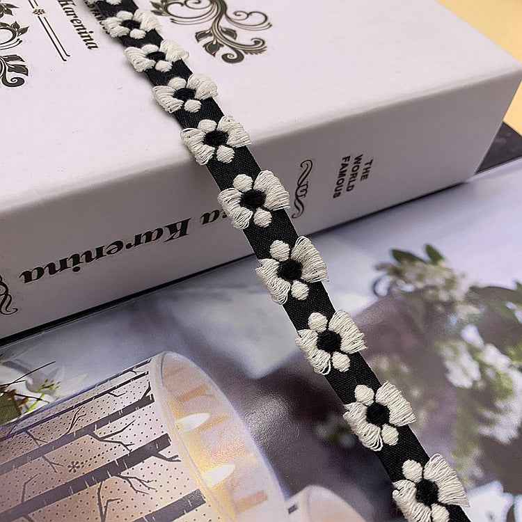 Jacquard-Spitzenband mit Blütenstickerei, dunkler Stoff mit weißen Blüten