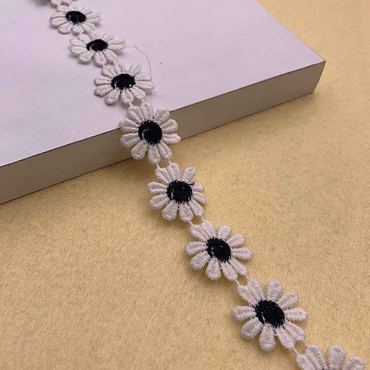 Daisy petal polyester lace trim with white flowers and dark black centers, decorative border