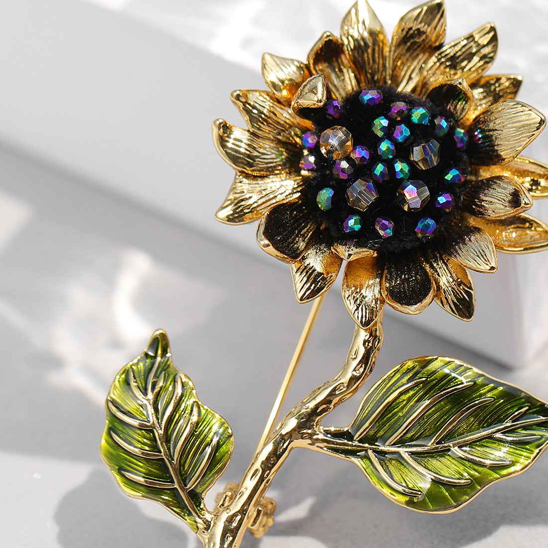 Nahaufnahme: goldfarbene Sonnenblumenbrosche mit funkelnden Regenbogen-Kristallen
