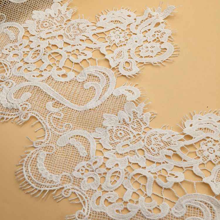 White lace trim close-up with floral appliqué loops and detailed net background