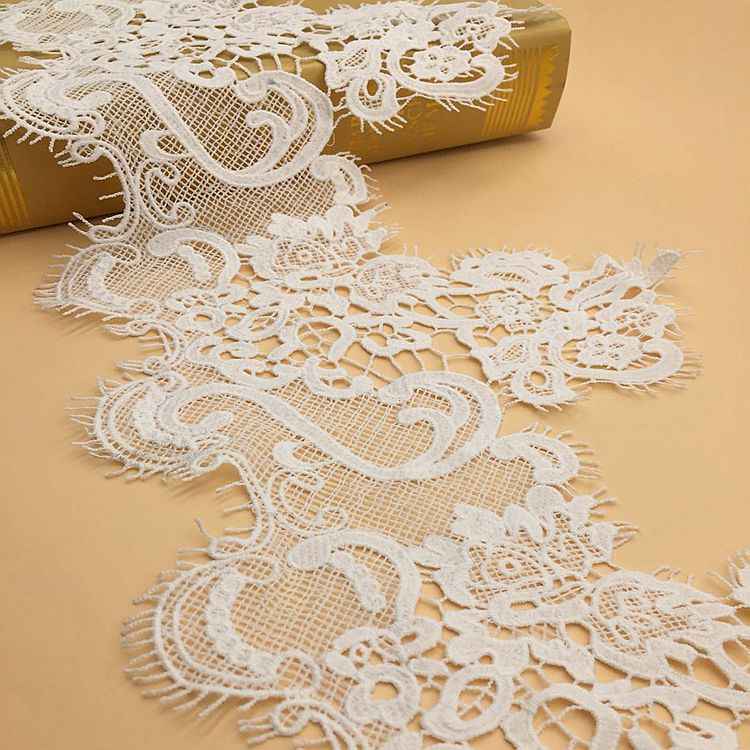 White water-soluble lace trim with swirling floral patterns and scalloped edge
