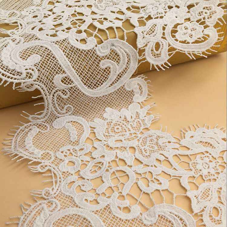White lace polyester trim close-up with lace floral medallions and cutout net texture