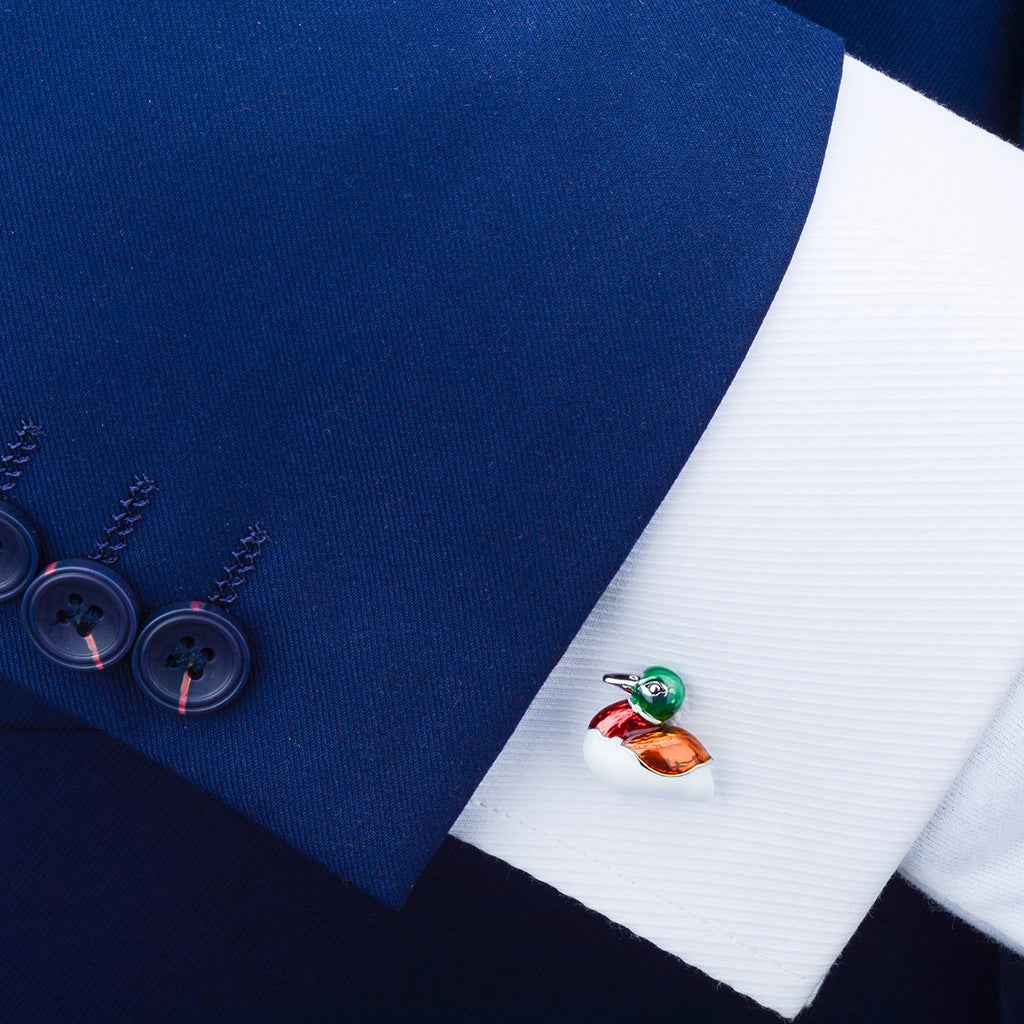 Duck-shaped cufflinks on a dress shirt cuff; green, orange, and red enamel with silver