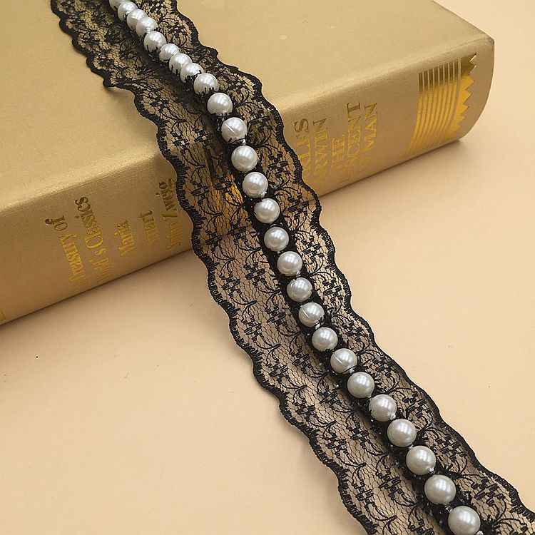 Nastro in pizzo nero con perle finte bianche, elementi rotondi lungo la fascia