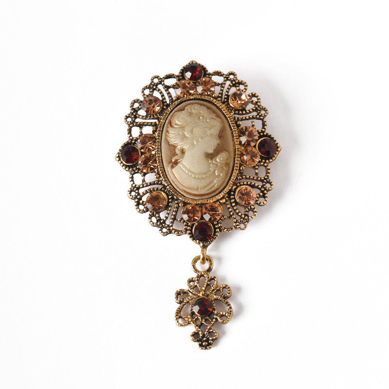 Gold queen cameo rhinestone brooch with oval portrait and red-gem border, dangling charm