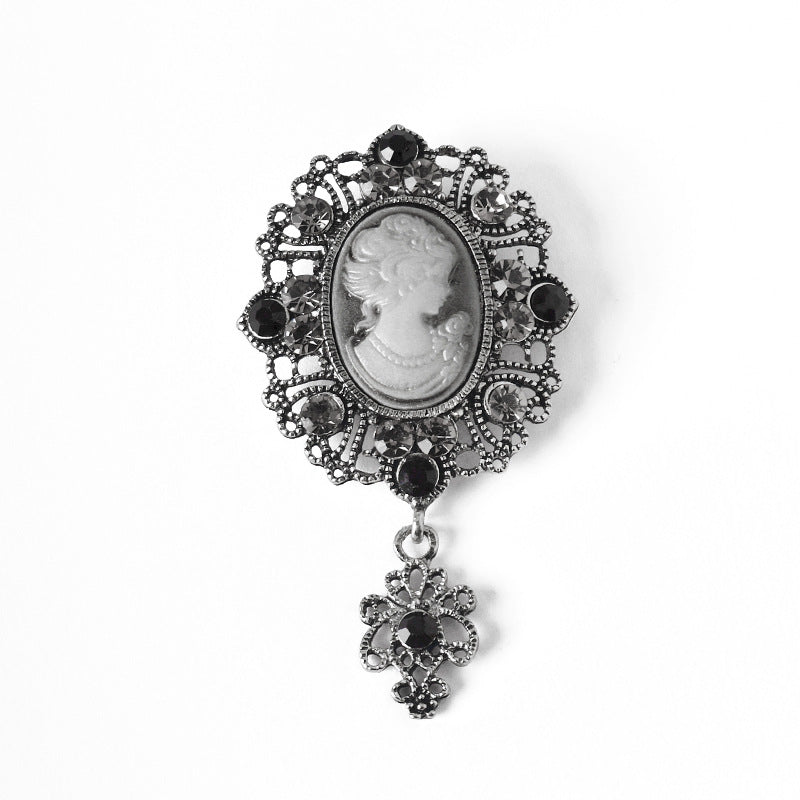 Silver queen cameo rhinestone brooch with oval portrait and dark rhinestone border, dangling charm