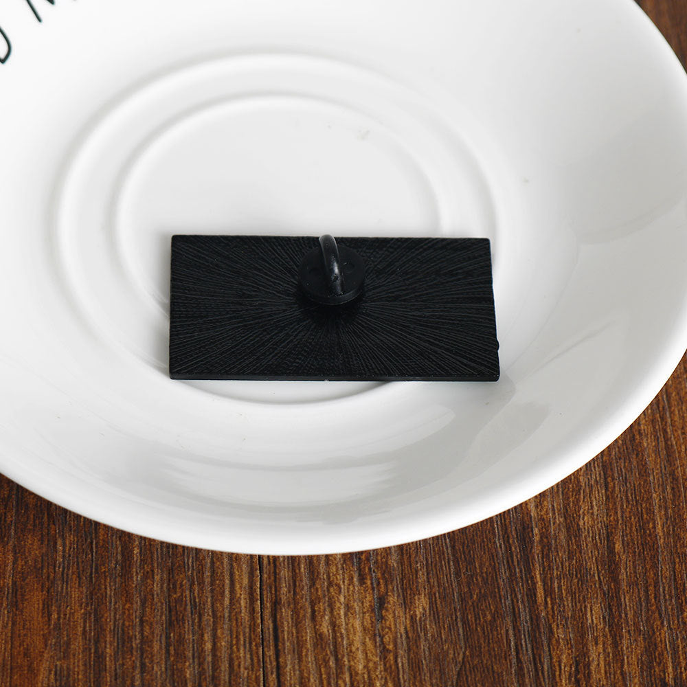 Back of money-themed lapel pin, black rectangular piece with pin clasp