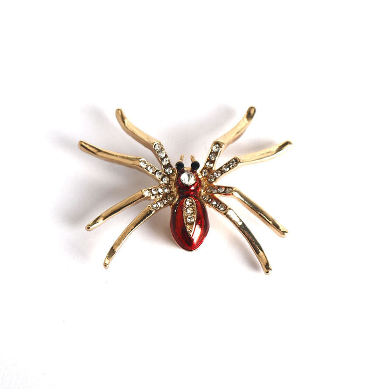 Gold-tone glitter spider brooch with red teardrop body and clear rhinestone legs