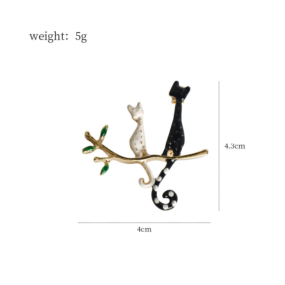 Cat-on-branch brooch pair: black and white kitties with green accents, 4cm wide