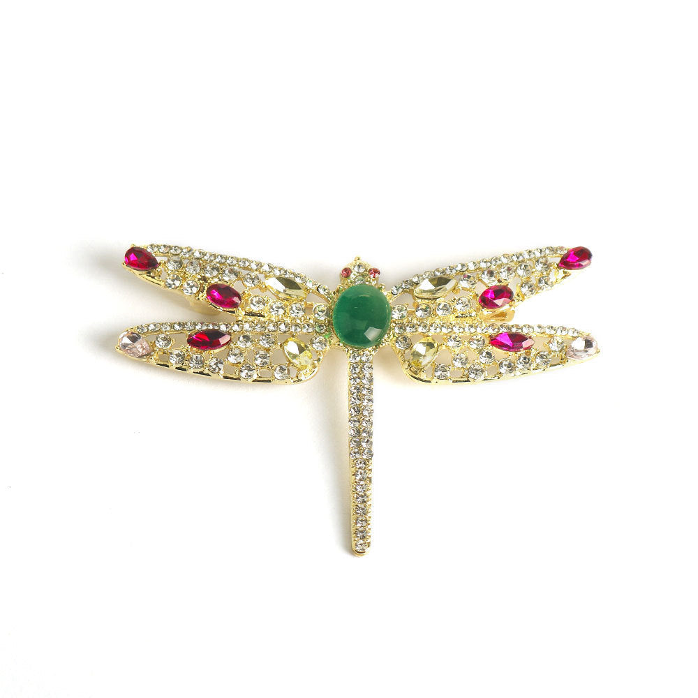 Gold-tone dragonfly brooch pin with green round center and pink crystal accents