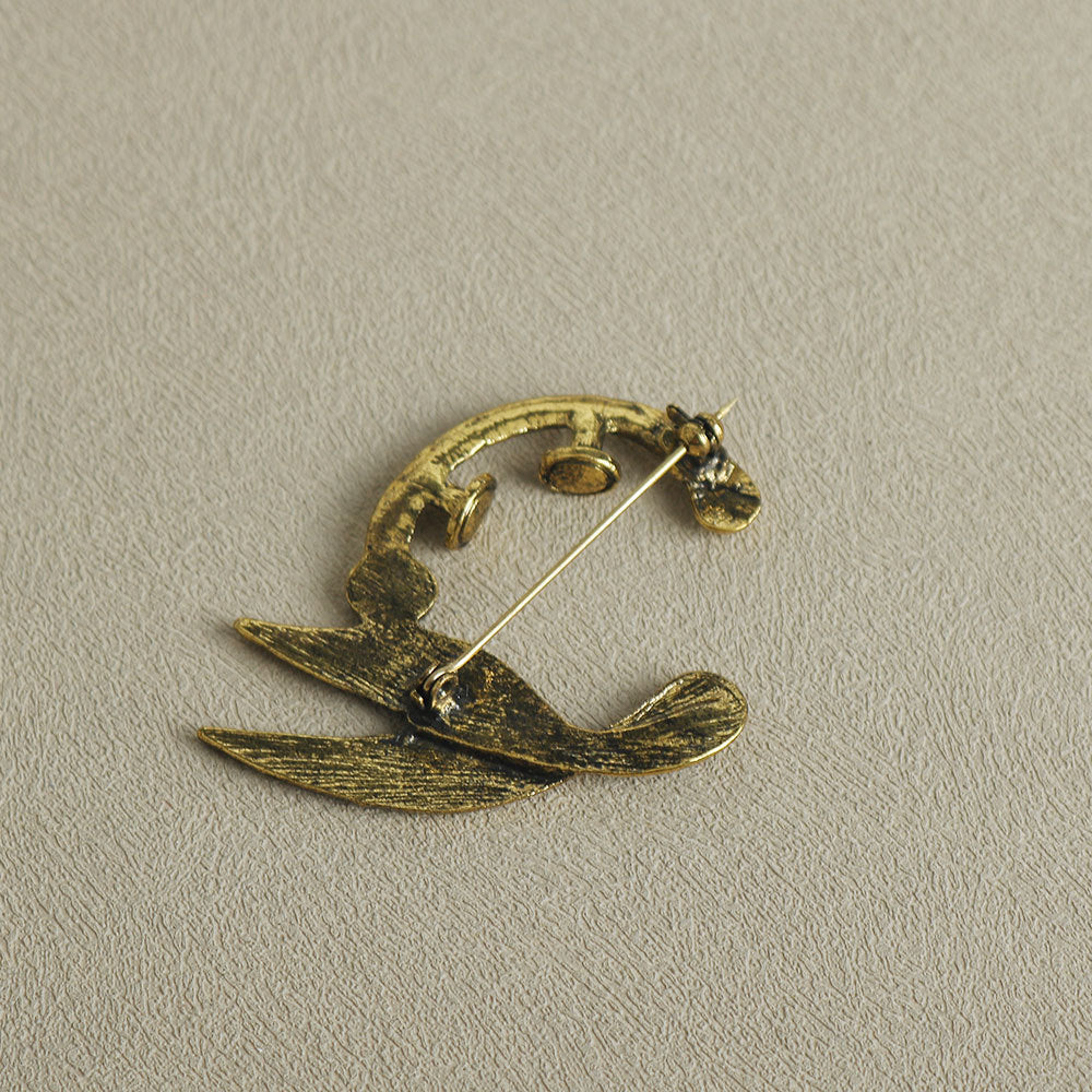 Gold-tone crescent brooch pin with pointed wing/feather shapes and pin clasp