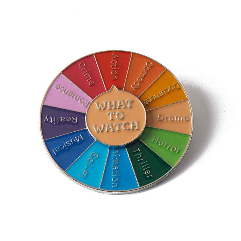 Circular spinner brooch 'WHAT TO WATCH' with colorful segmented wheel and gold rim