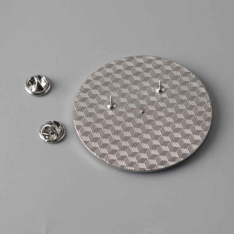 Back of circular spinner brooch: silver patterned disc with two pin backs