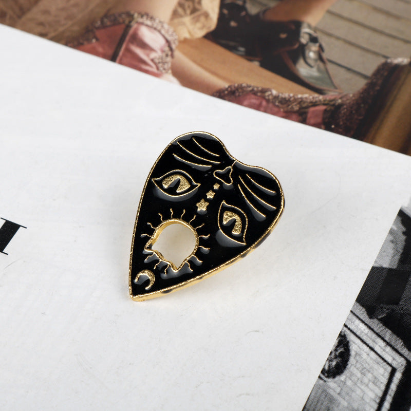 Gold-tone cat claw brooch with sunburst, crescent moons, and eye motifs