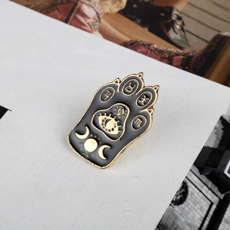 Gold-tone cat claw brooch with zodiac circles, paw emblem, and crescent moon