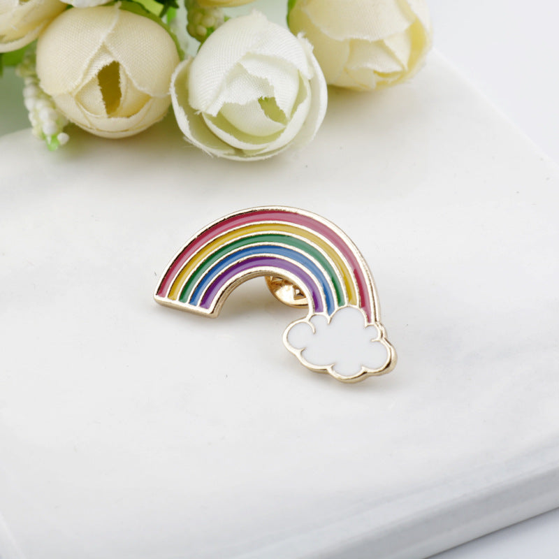 Metal rainbow bridge brooch with gold center and cloud accents at the ends