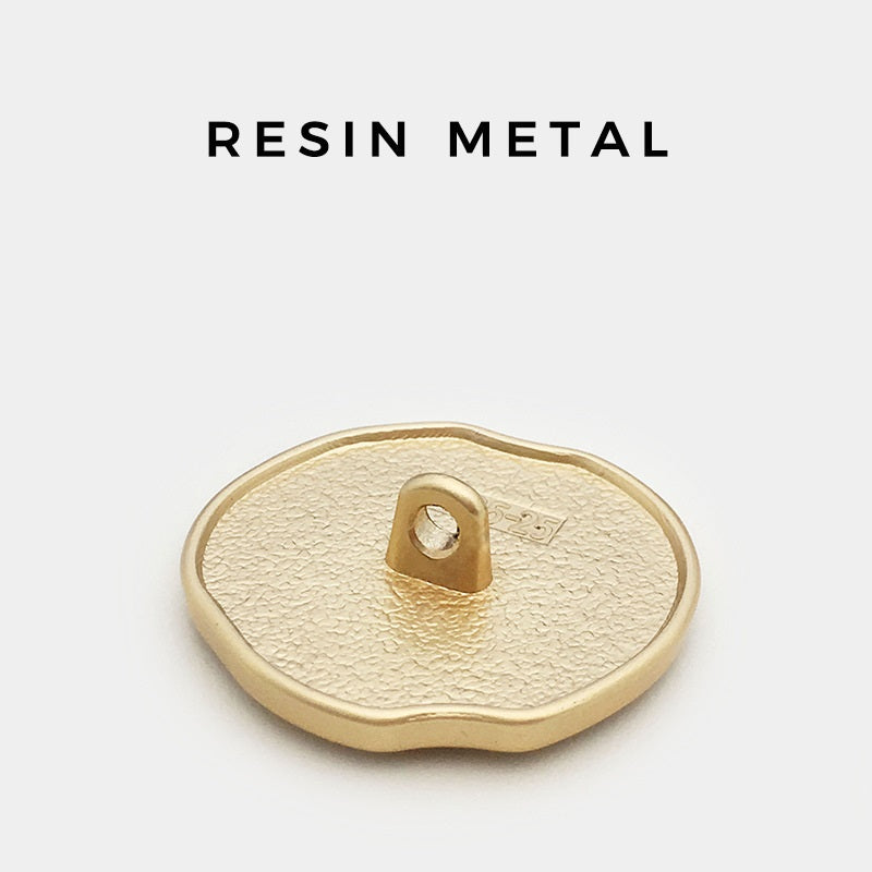 Back of irregular apple-shaped metal shank button, gold-tone textured base with eyelet