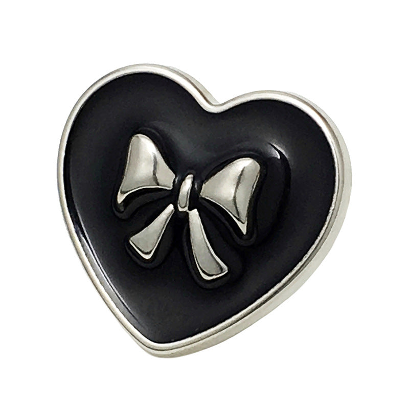 Black heart-shaped bow metal button, silver border and bow, front close-up