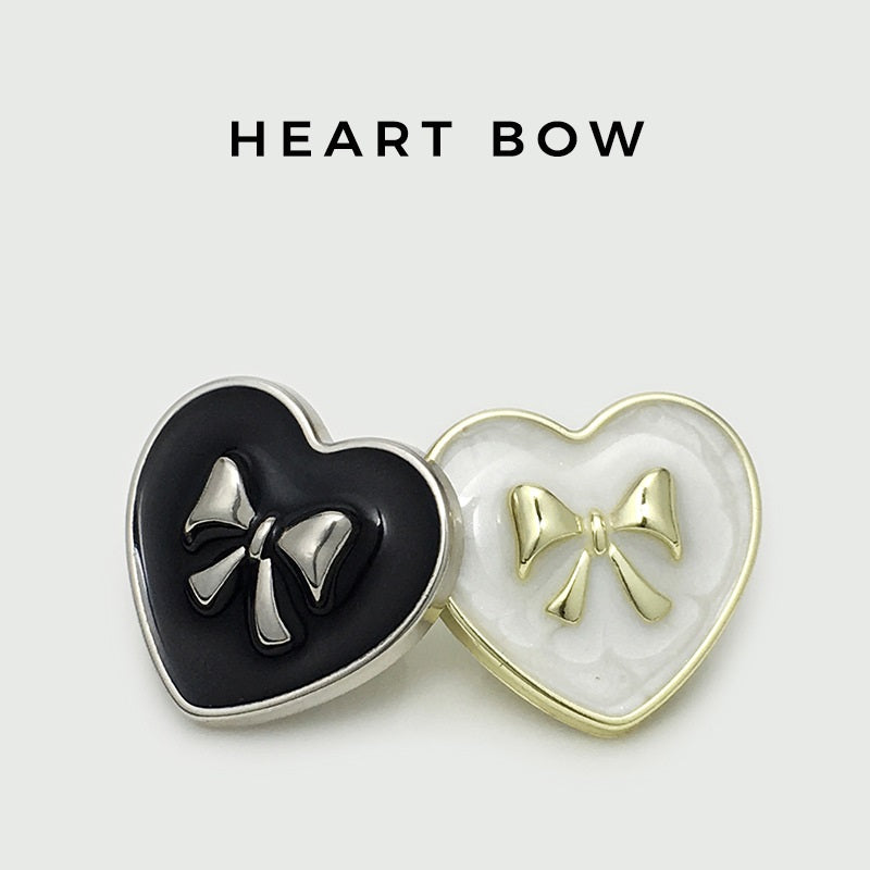 Black and white heart bow metal buttons with metallic bow details, paired view