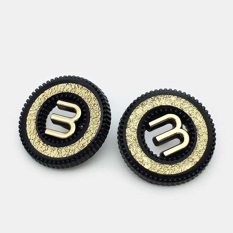 Two black hollow metal buttons with letter M, gold textured outer rim, shank