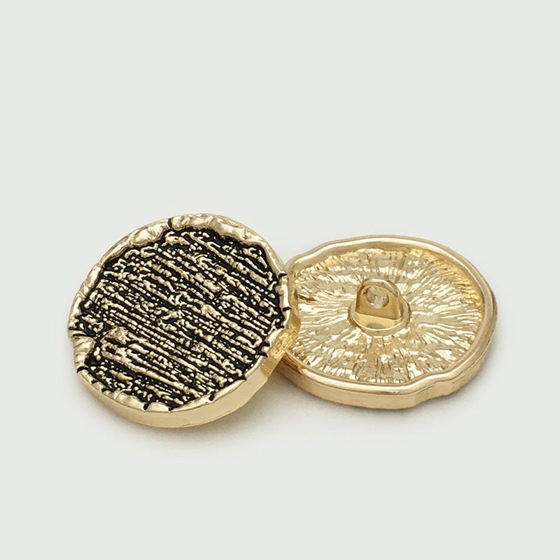 Gold-tone irregular round metal sewing button, back view with center shank