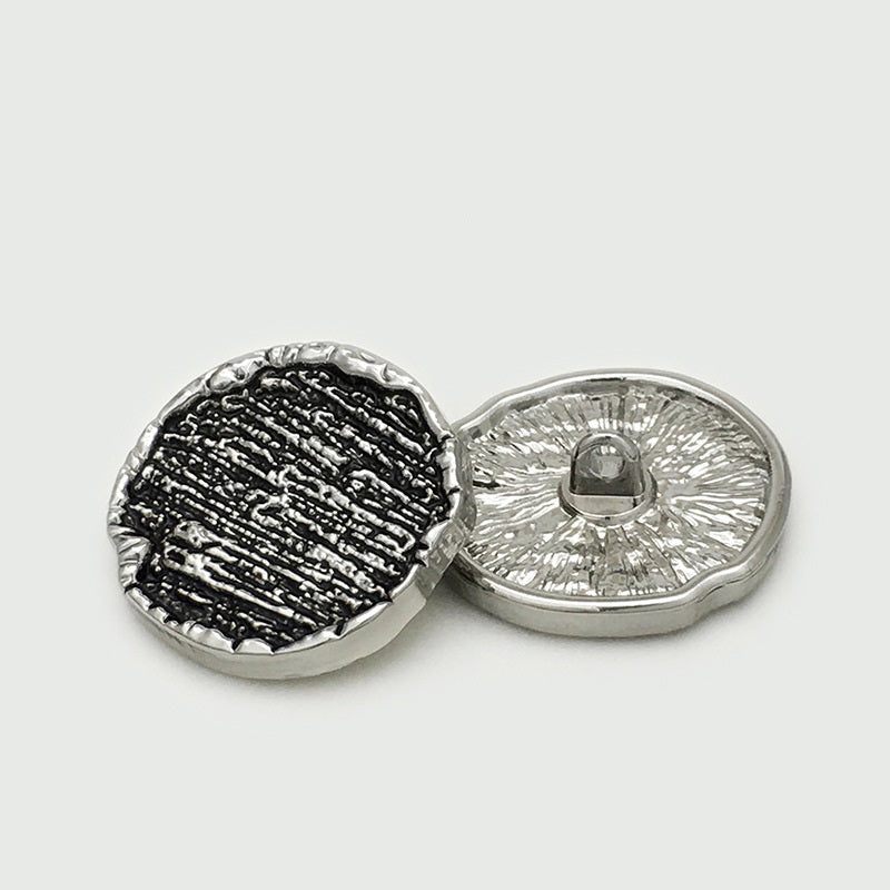 Silver-tone irregular round metal sewing button, back view with center shank