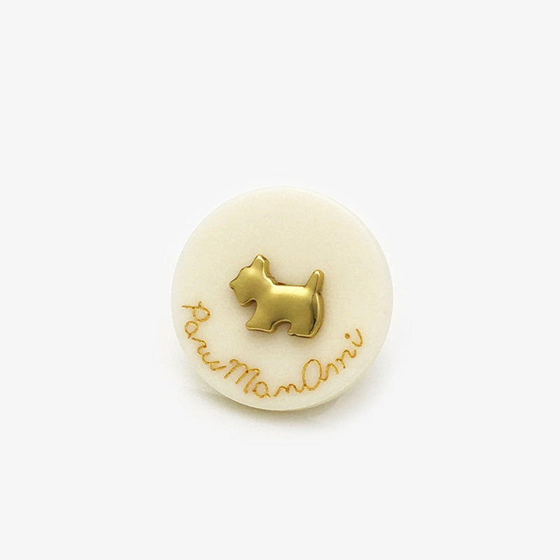 Cream round resin-metal dog button with gold dog silhouette and “Paw…more” script