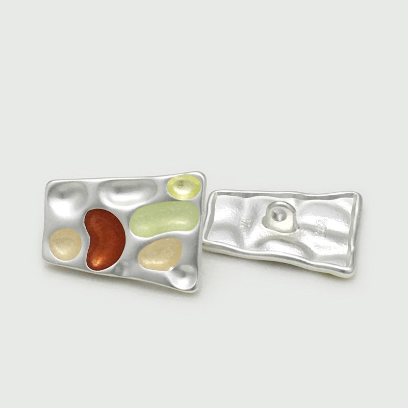 Silver tone trapezoidal metal button pair—front with pale yellow/green and purple inset