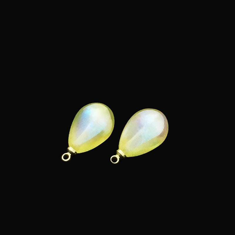 Two iridescent teardrop buttons: yellow and pale cream, each with metal loop