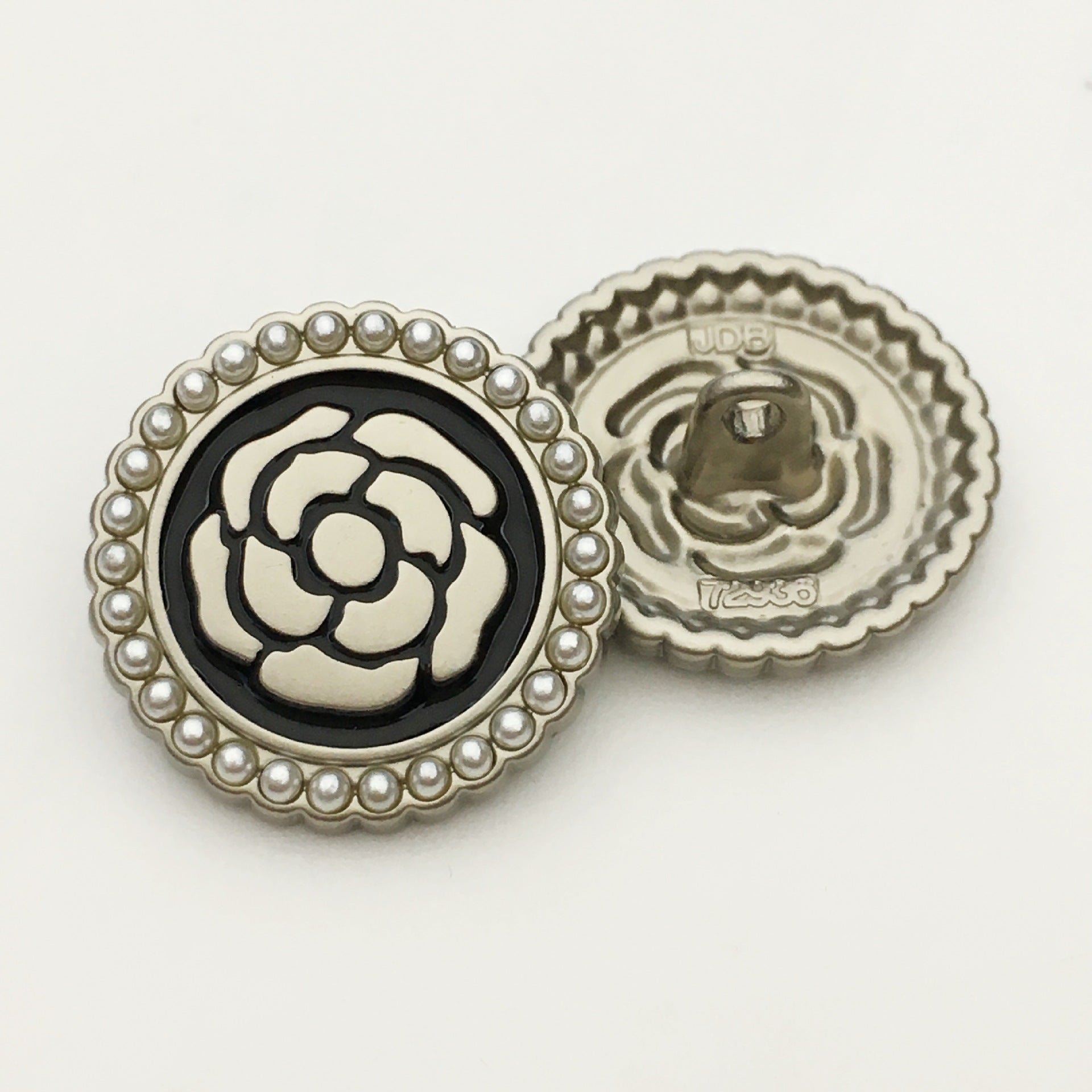 Round pearl-rim metal button with black-and-white floral rose face, back with visible shank