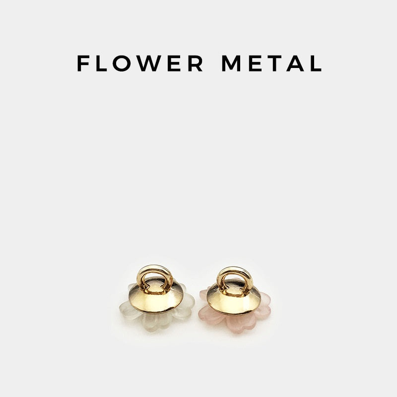 Gold-tone metal shank on transparent floral resin shirt buttons, front view