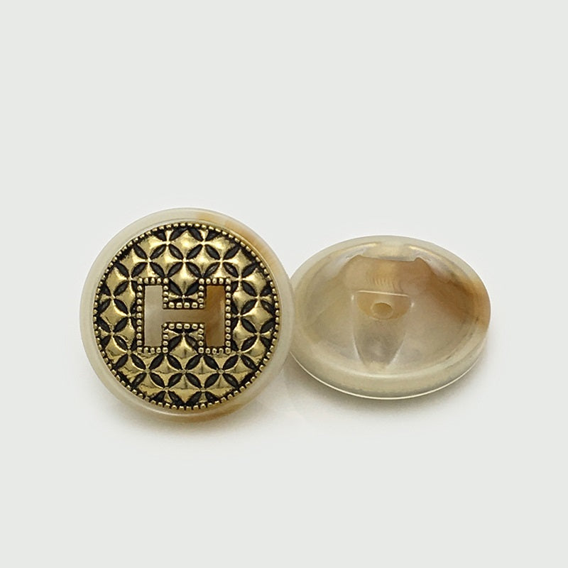 Beige round resin H button with gold filigree pattern, side/back view