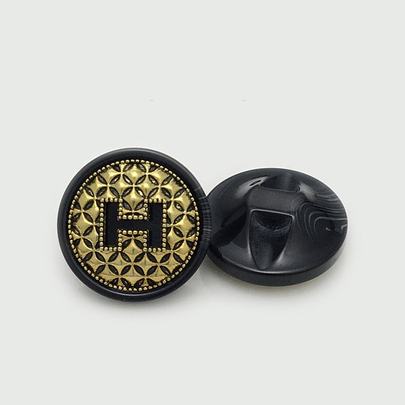 Black round resin H button with gold floral border, shown with back
