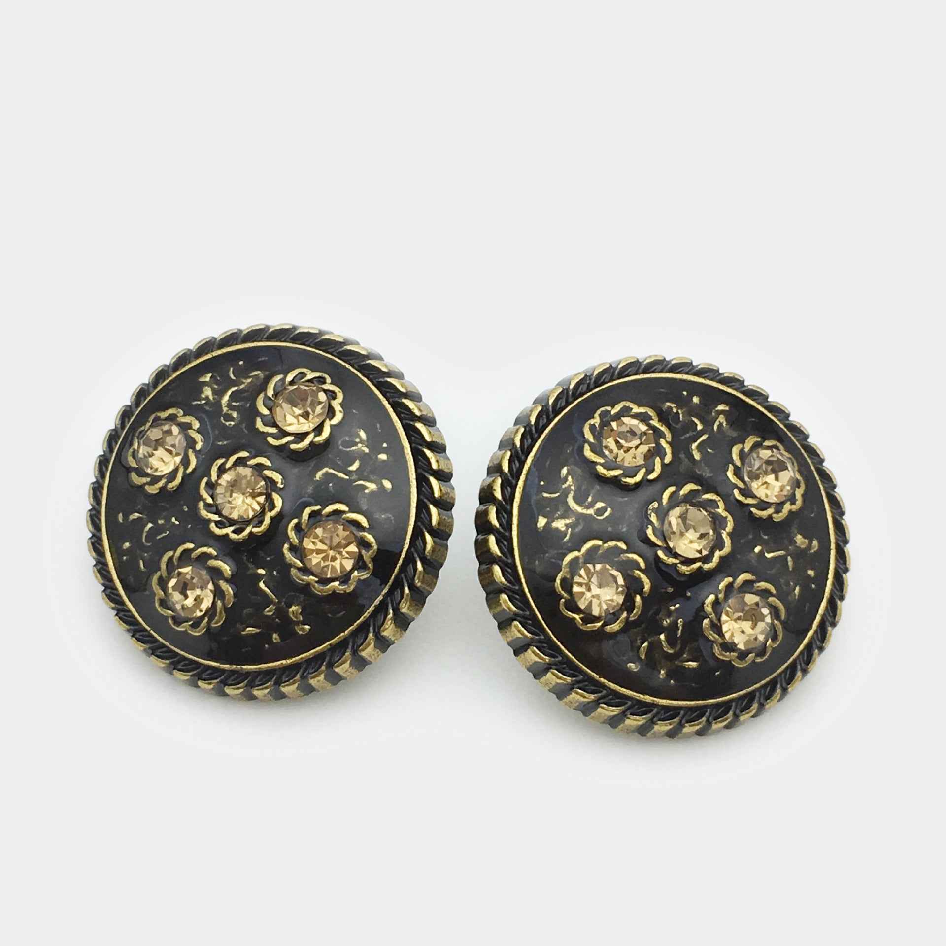 Bronze-toned metal coat button pair, round black base with ornate floral diamond rhinestones