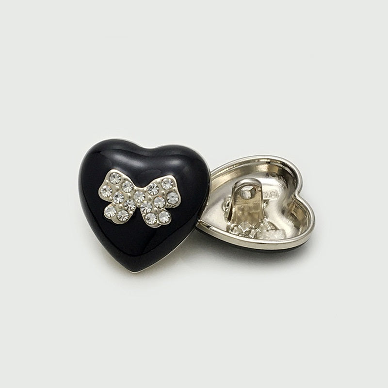 Black heart-shaped metal button with crystal bow front and gold back