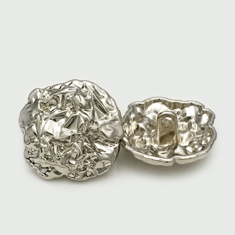 Pair of oversized silver metal buttons, textured irregular oval, one back with loop