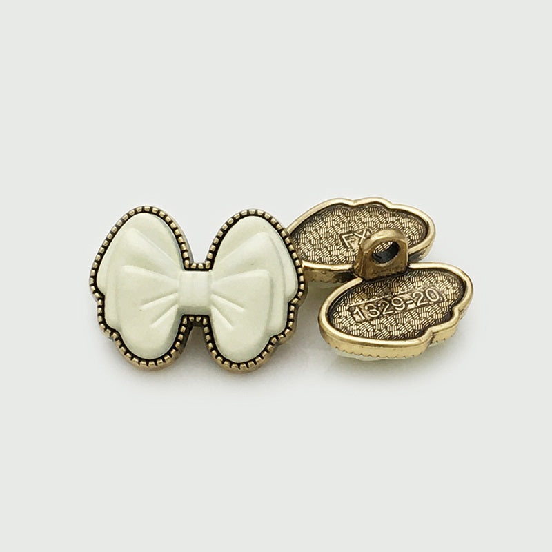 White 3D bow resin button, back view, gold shank marked 1329-20
