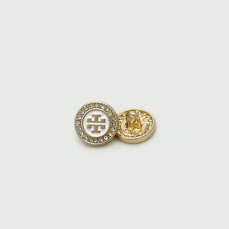 Gold shirt button with crystal rim, white logo front and visible metal back