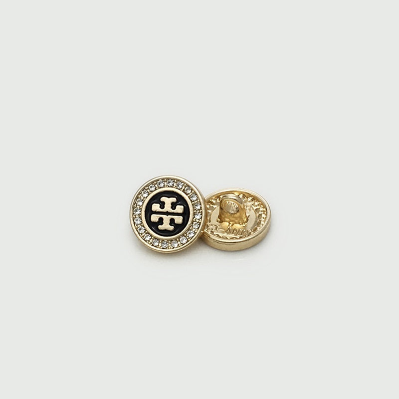 Gold shirt button with crystal rim, black logo front and visible metal back