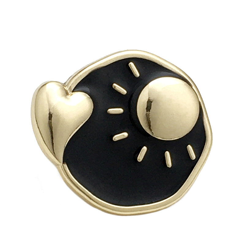 Botón metálico sol y luna irregular negro con corazón dorado y líneas de rayos