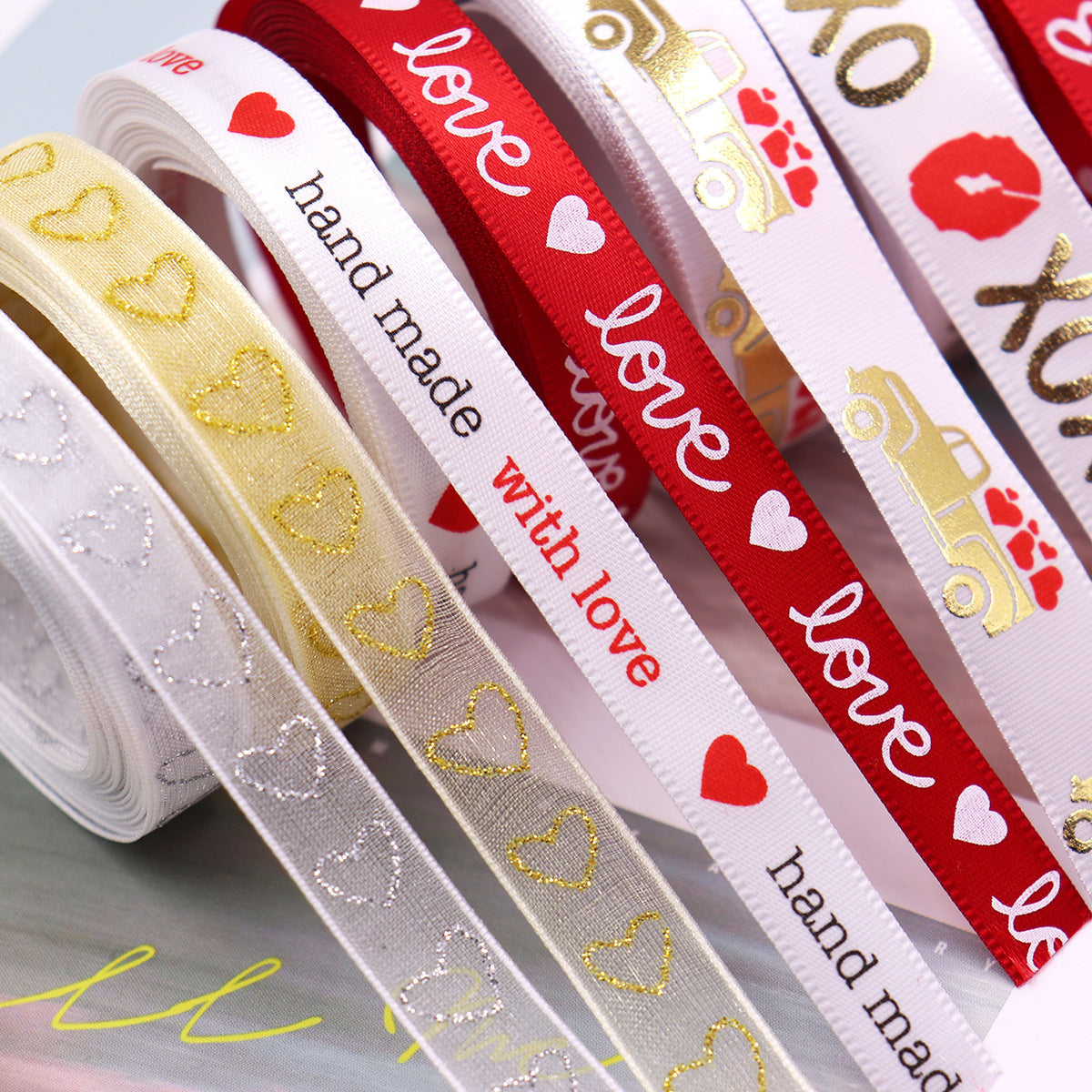 Close-up hot stamping ribbon: gold hearts, “hand made with love,” and red XOXO bands