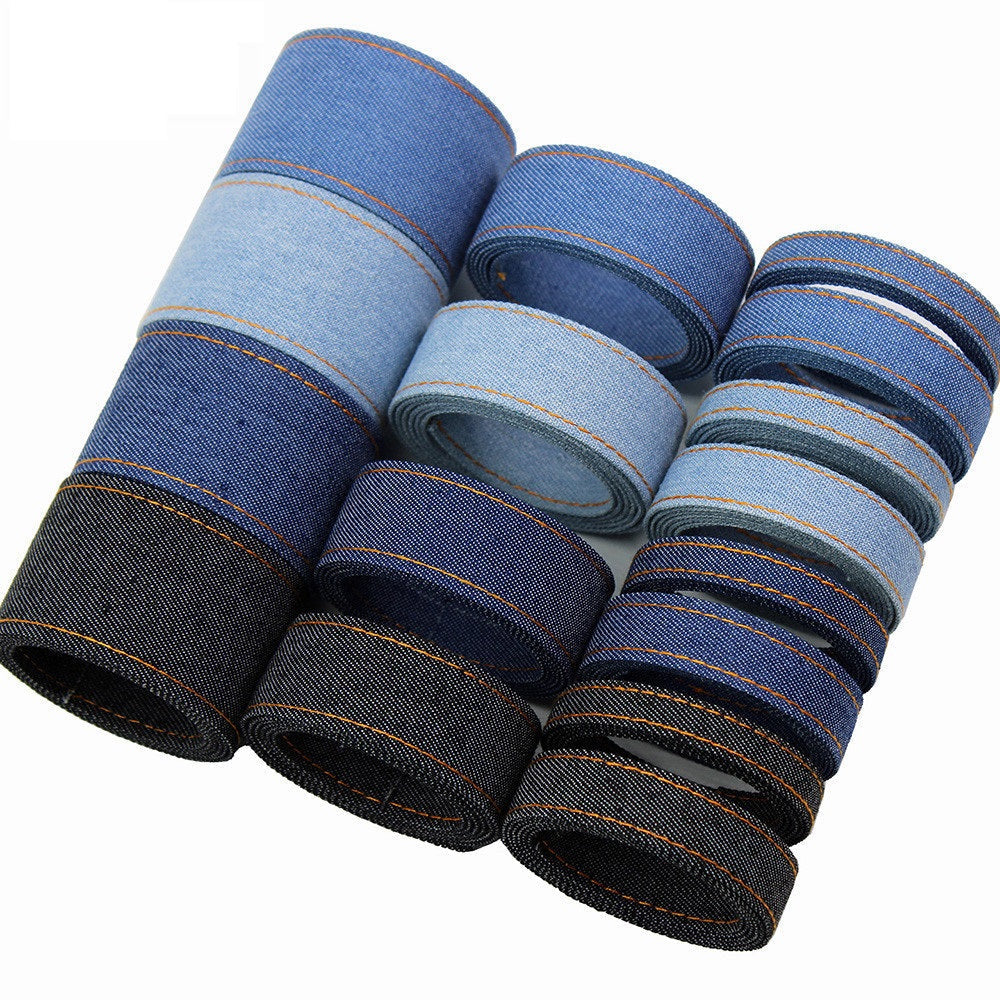 Denim fabric ribbon spool in blue tones with orange edge stitching